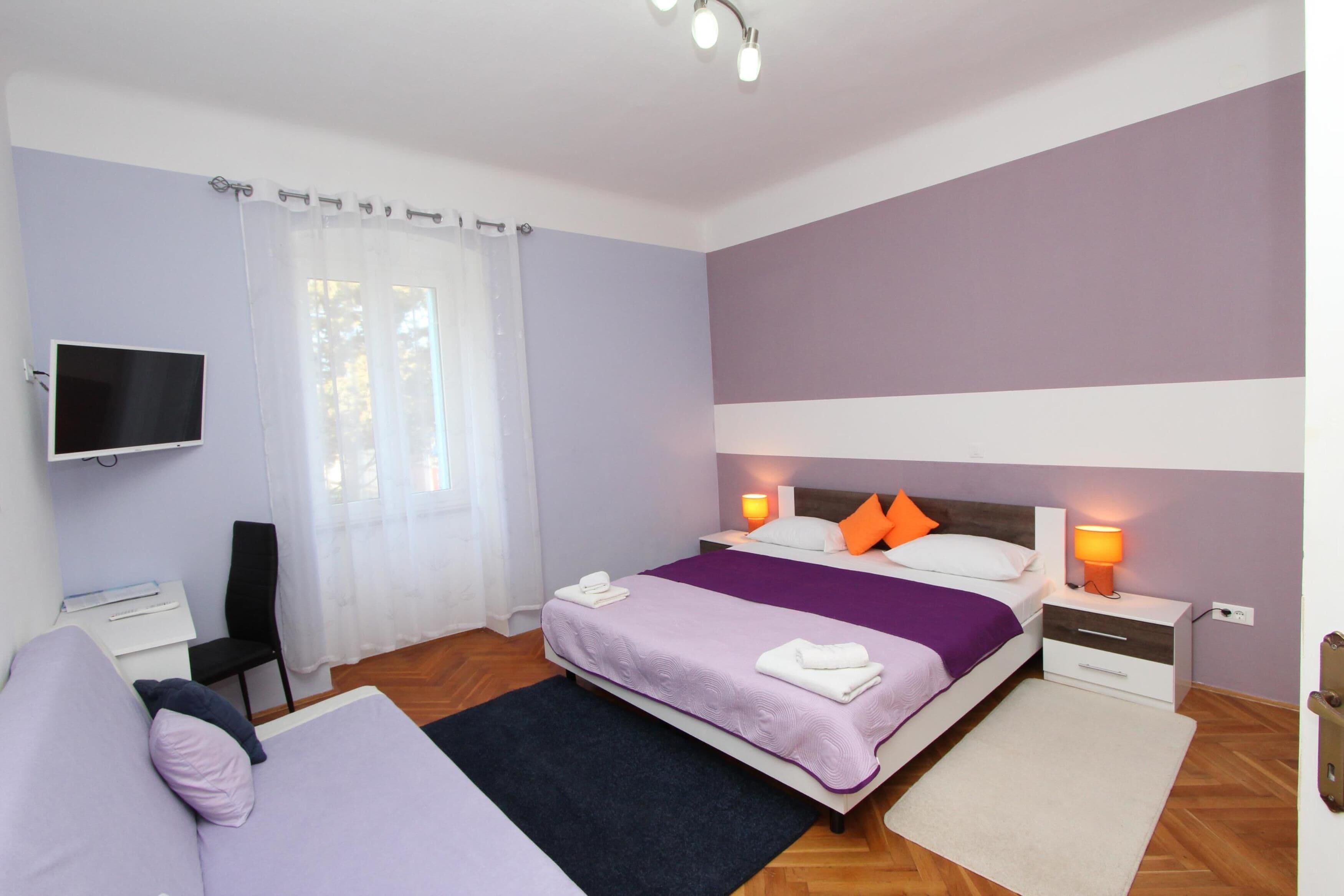 Una camera da letto con un letto, comodini, televisione, una poltrona e una scrivania.