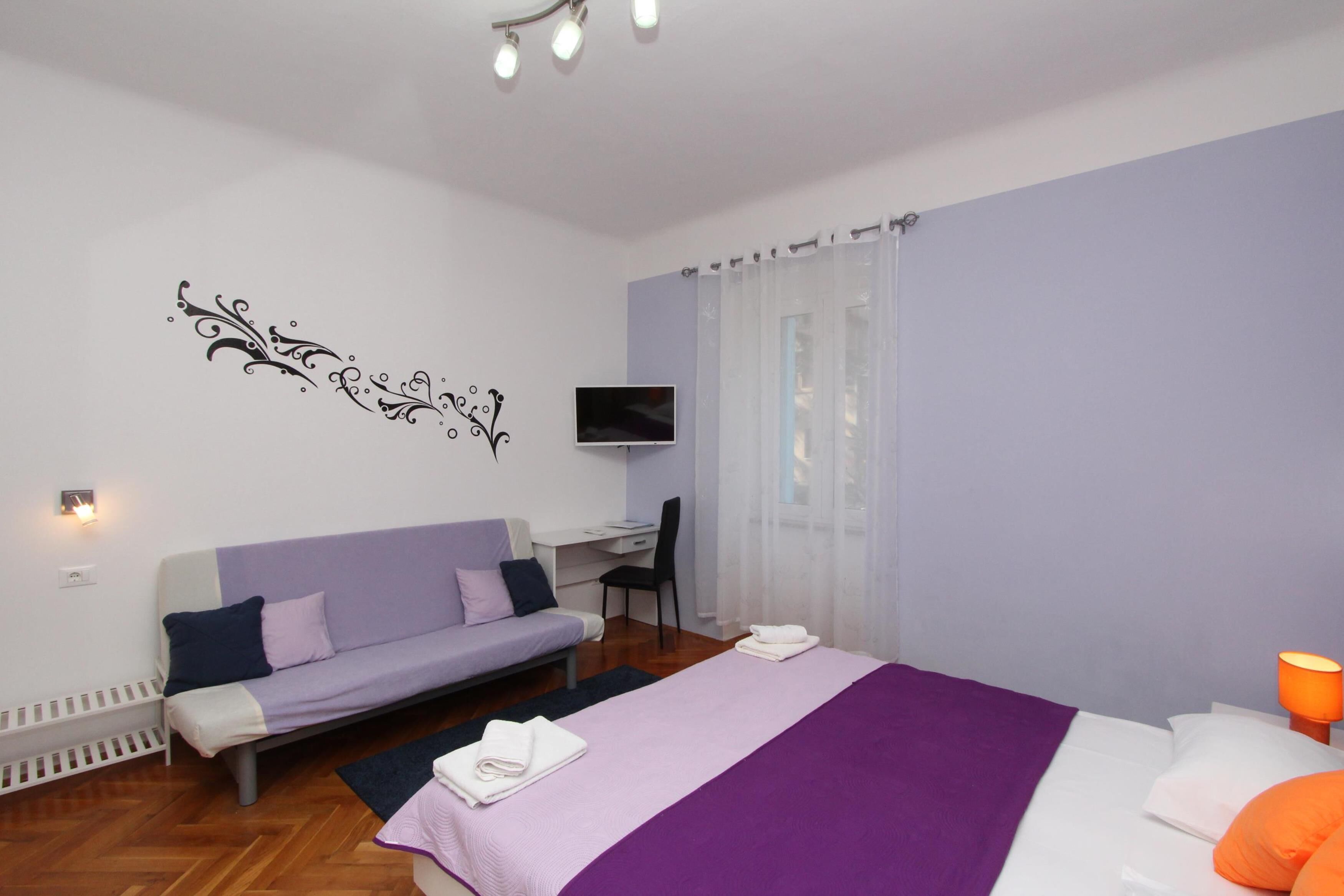 Un dormitorio moderno con cama, sofá, escritorio y televisor.