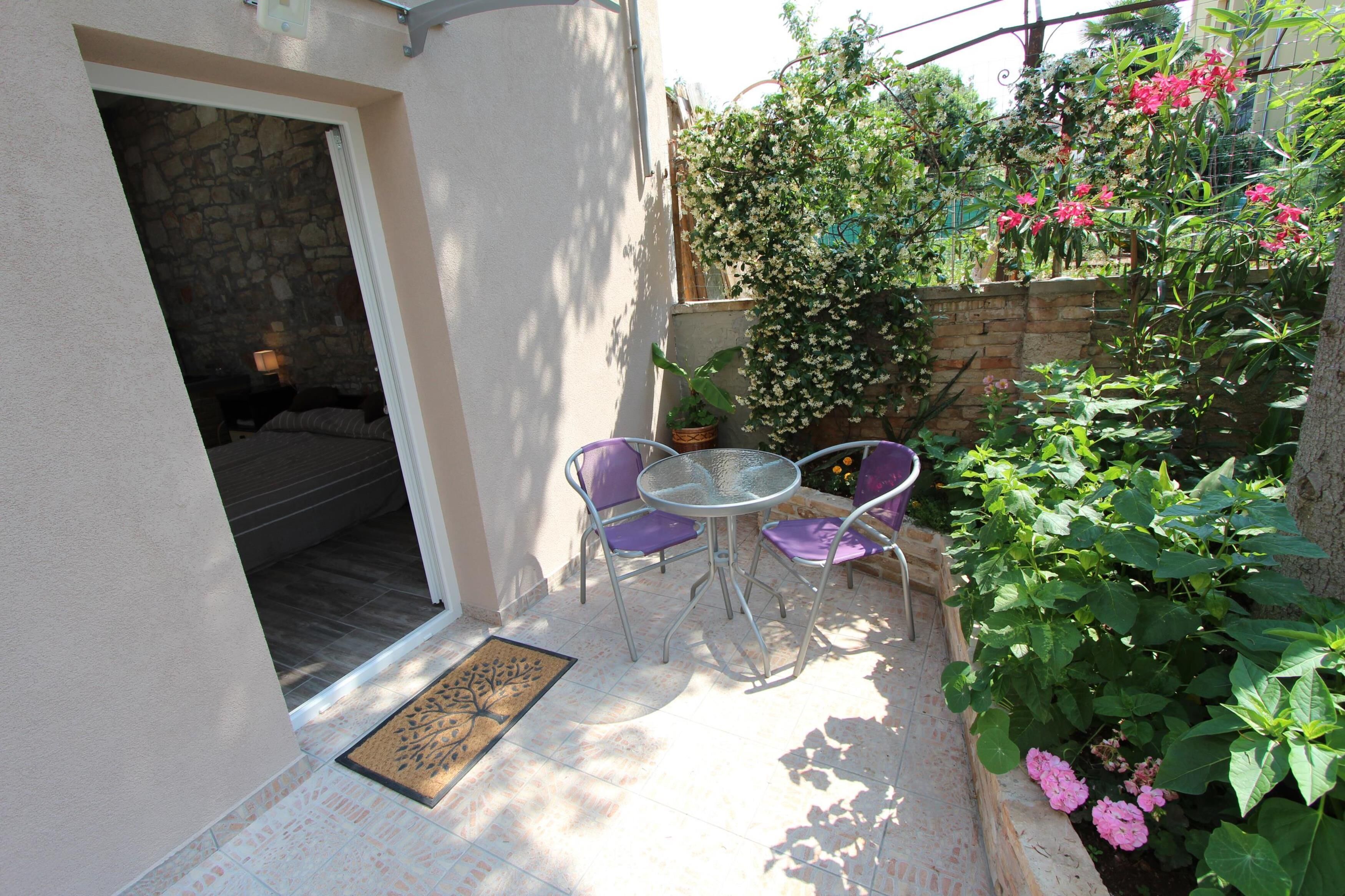 A patio with a stone wall, a small table, and purple chairs.