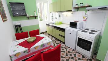 A compact kitchen with a dining area, featuring a microwave, stove, and a small refrigerator.