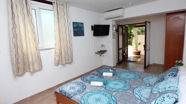 A bedroom with a bed, curtains, a TV, and a view of the outside. - Studio Sea (Rovinj)