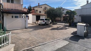 A residential street with a white car parked in front of a house, a tree, and a clear blue sky. - Studio Sea (Rovinj)