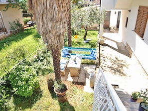A balcony with a view of a garden, a blue bench, and a potted plant. - Studio Sea (Rovinj)