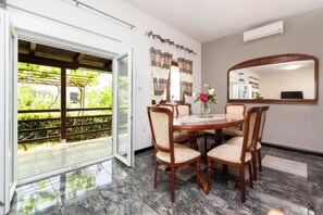A dining area with a table and chairs, a large mirror, and a view of greenery through an open door. - Apartments Sena (Rovinj)