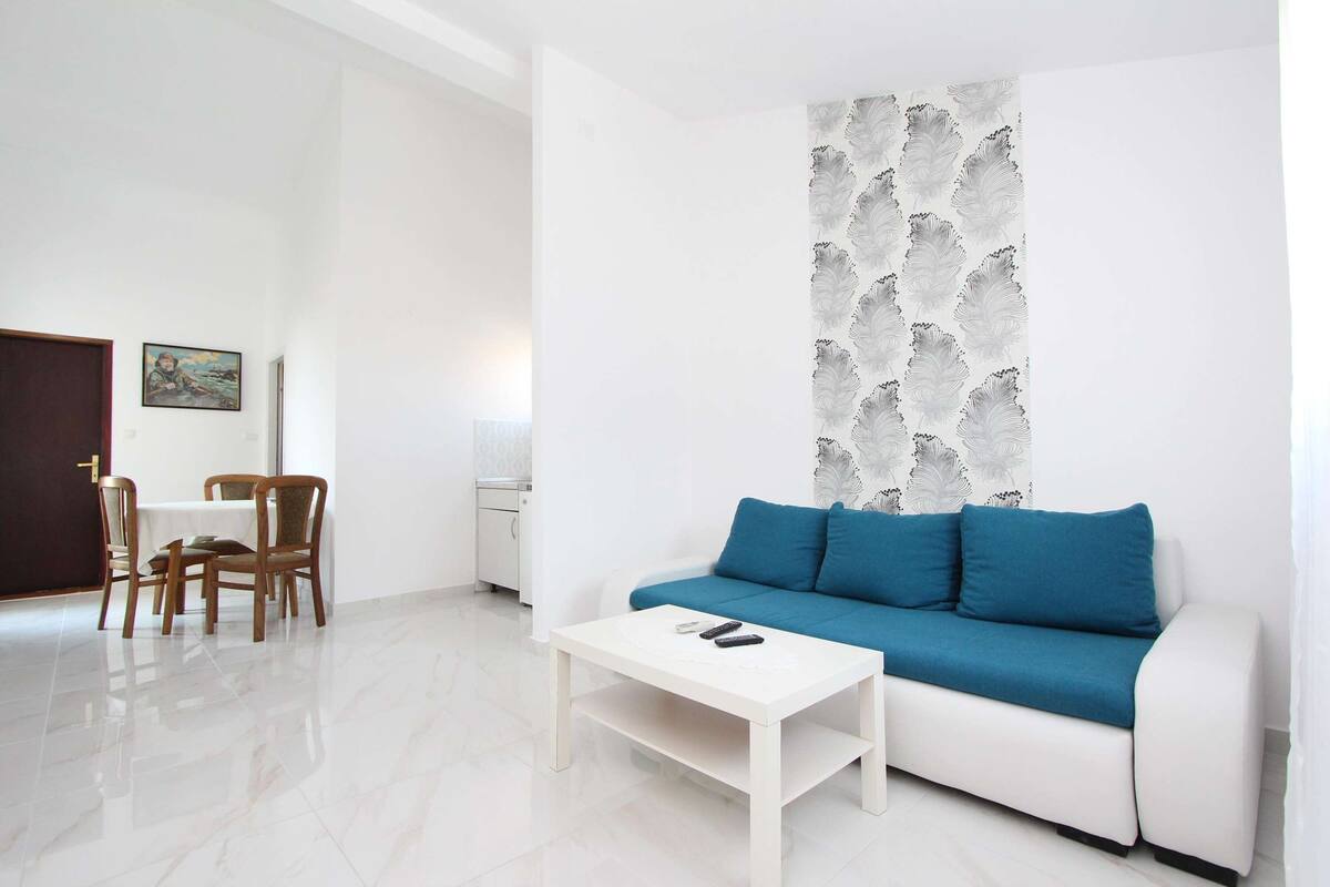 A living room with a white sofa, blue cushions, a white coffee table, and a patterned wall.