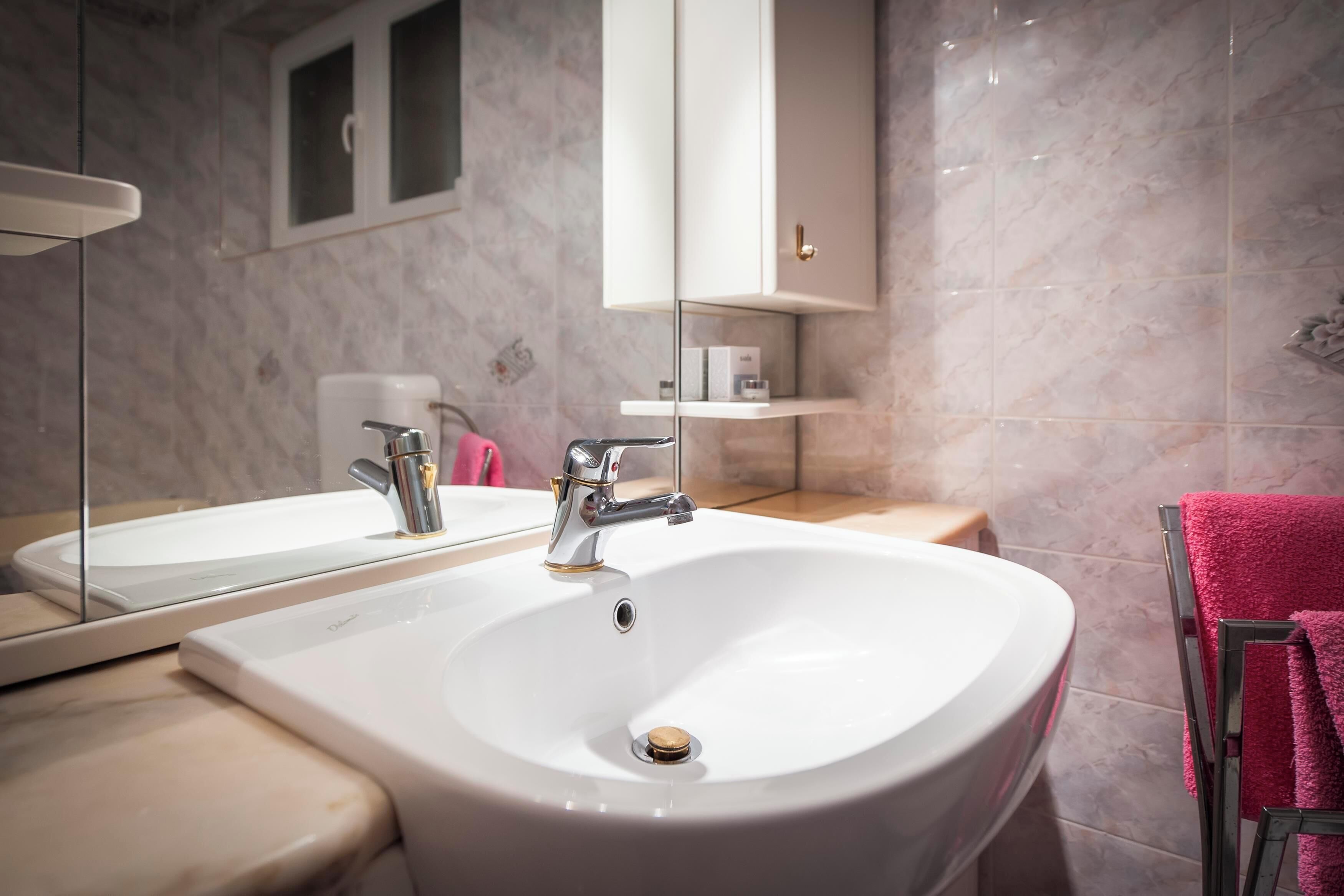 Ein Badezimmer mit einem großen, weißen Waschbecken, einem Spiegel und einem Schrank darüber.