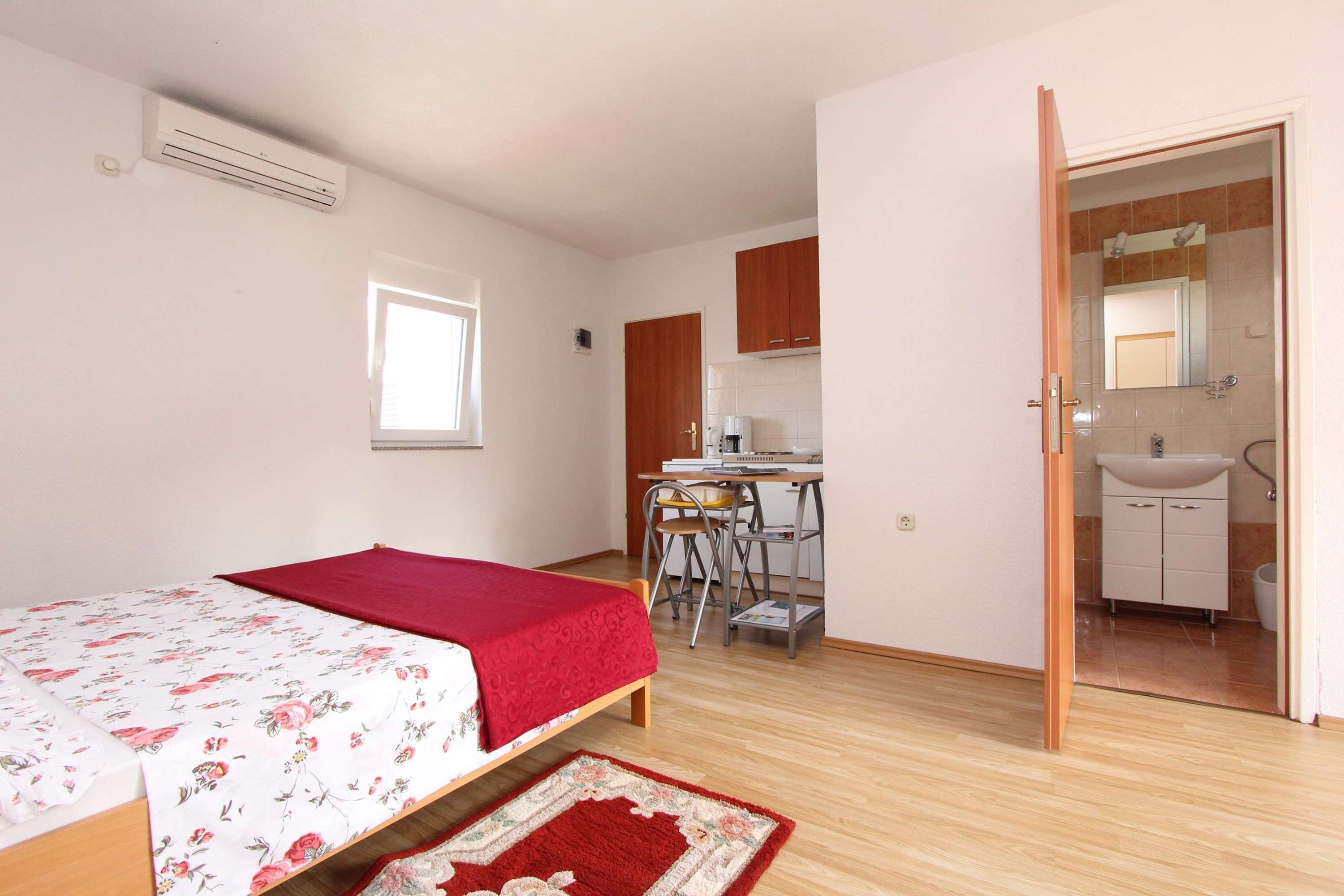 A bedroom with a bed, a desk, and a bathroom visible through an open door.