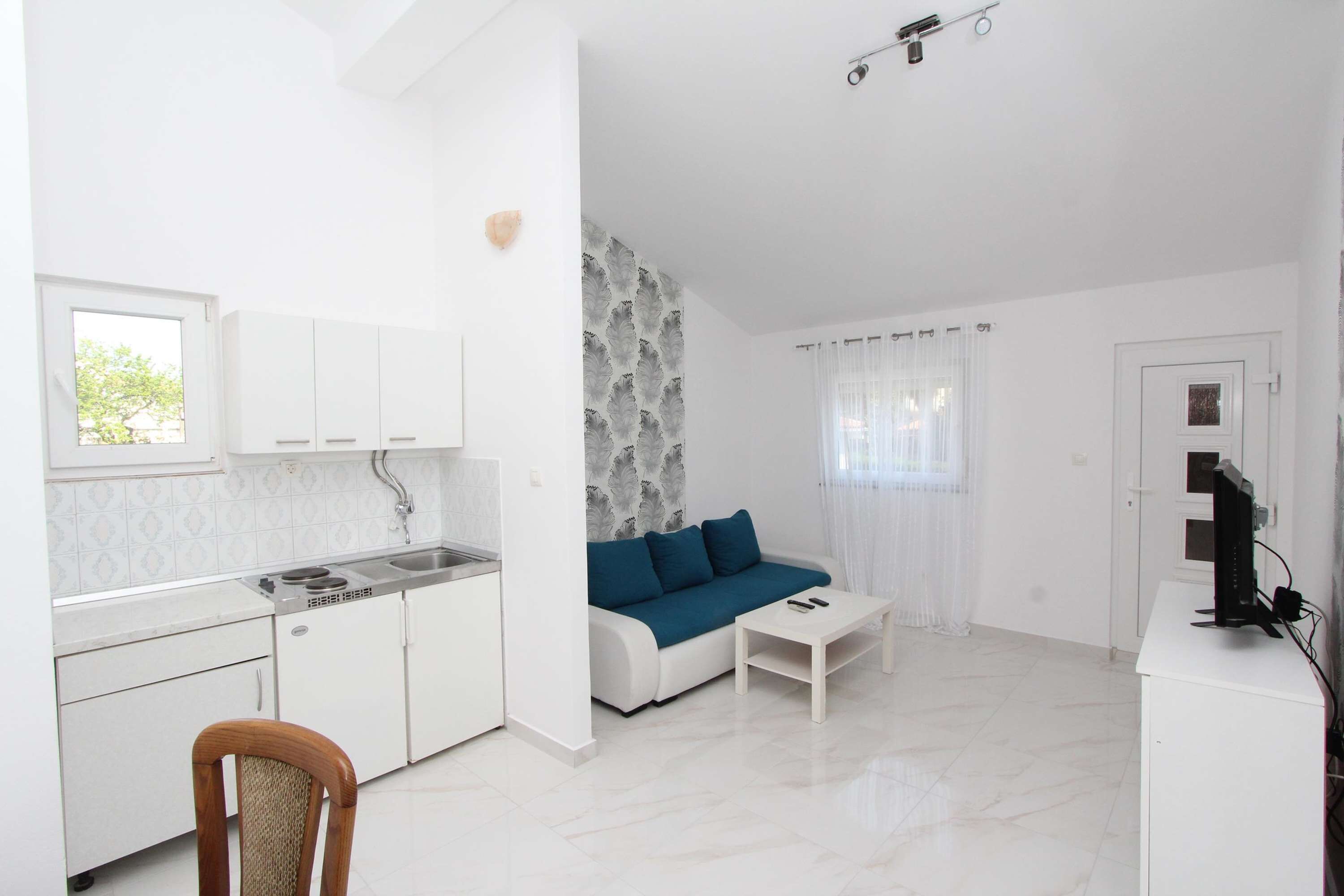 Un espacio habitable compacto con kitchenette, un sofá, una mesa de centro y un televisor.