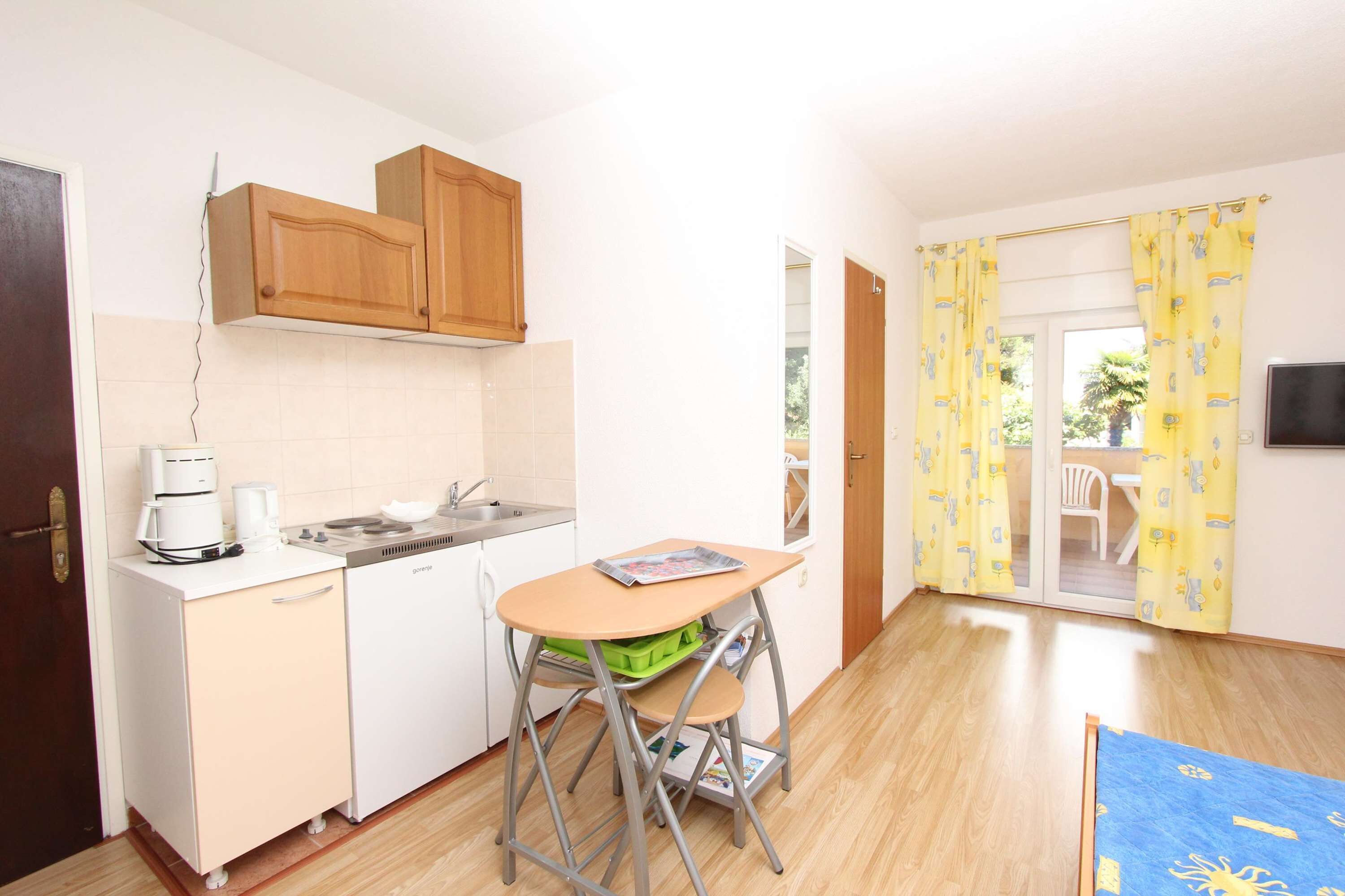 A compact kitchen with a sink, a coffee maker, and a small dining table.