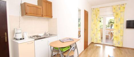 A compact kitchen with a sink, a coffee maker, and a small dining table.