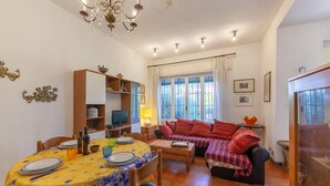 A cozy living room with a sofa, a dining table set with plates and glasses, a television, and a bookshelf. - Pet friendly apartment in Tirrenia -PI- (Tirrenia -PI-)