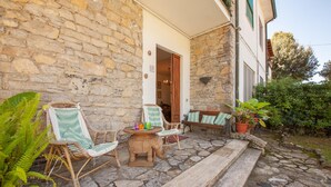 A stone building with a porch, wicker chairs, a small table, and potted plants. - Pet friendly apartment in Tirrenia -PI- (Tirrenia -PI-)