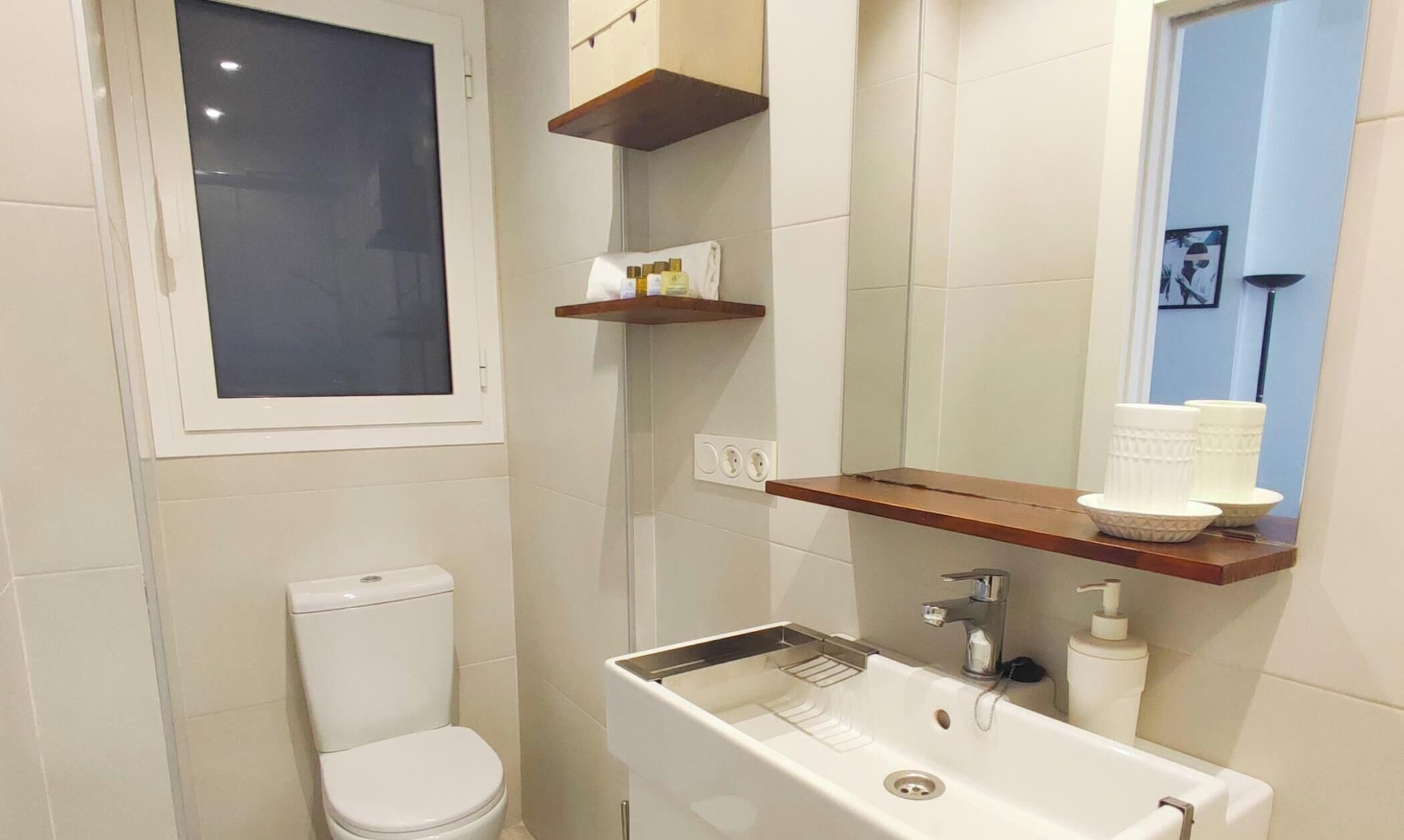 Een badkamer met toilet, wastafel, spiegel en raam.