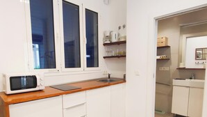 A compact kitchen with a microwave, wooden countertop, white cabinets, and a window. - Skyline Jacuzzi Living4malaga (Málaga)