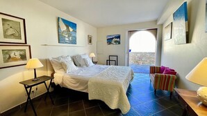 A bedroom with a bed, bedside tables, a chair, and artwork on the walls.