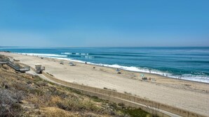 Ein Strand mit einer Betonpromenade, einem Rettungsturm und blauem Himmel.