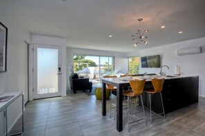 A modern kitchen with a dining area, large windows, and a view of the outdoors. - Wind (1 bedroom / 1 bath) (Carlsbad)