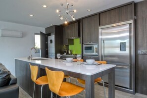 Kitchen features a central island with a white countertop and four chairs, a stainless steel refrigerator, and an oven.