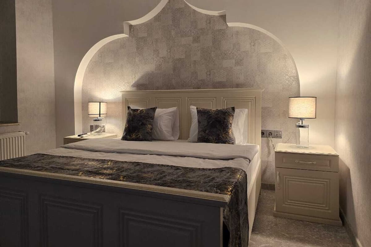 A bedroom with a large bed, two bedside tables, and a headboard with a unique design.