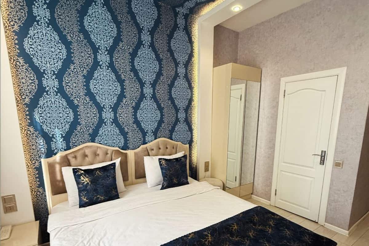A bedroom with a bed, a nightstand, a wardrobe, and a mirror.