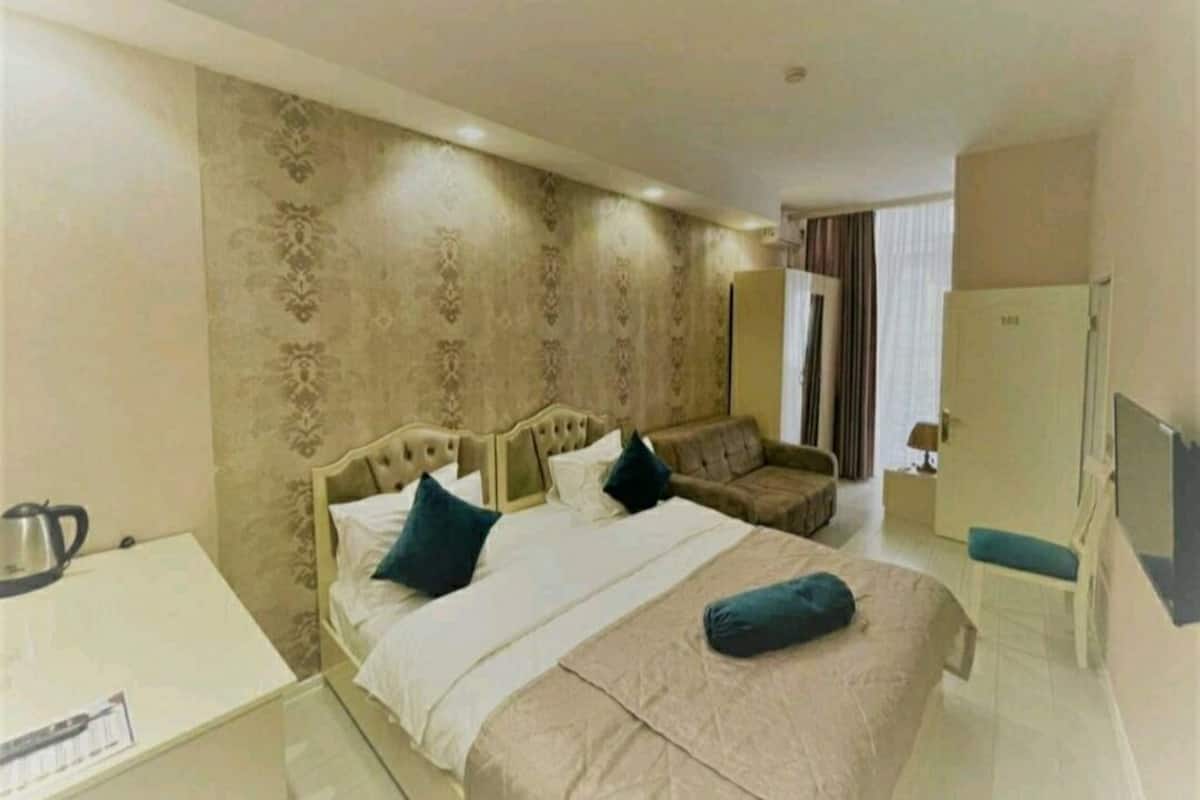 A hotel room with a bed, a sofa, a desk, and a TV.