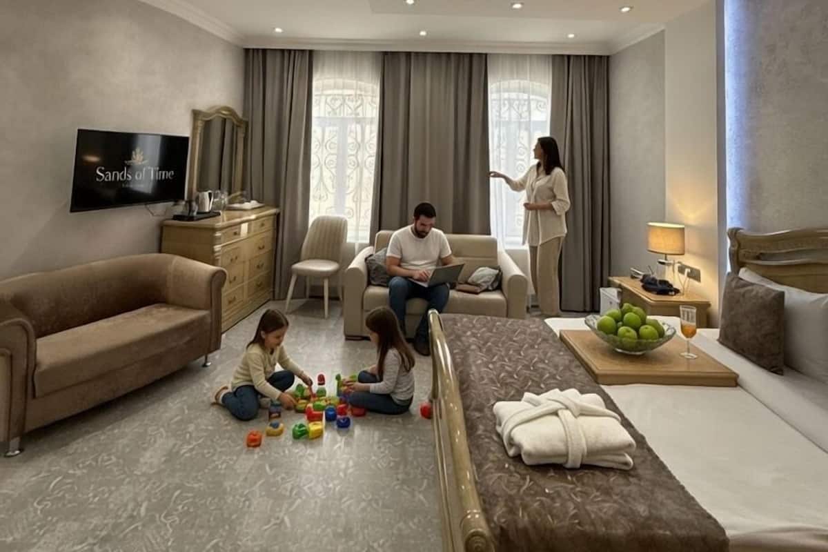 A hotel room with a sofa, a TV, a bed, and a dining area with a table and chairs.