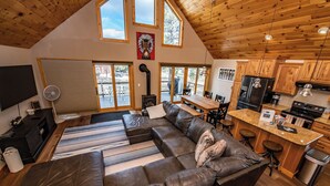 A spacious living area with a large leather sofa, a dining table, and a kitchen with wooden cabinets and modern appliances. - Hot Tub! Close to Fishing, ATV, Hiking, Rafting, Rivers! (Pagosa Springs)