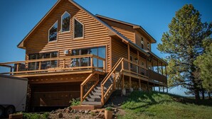 A two-story log cabin with a balcony and a garage. - Hot Tub! Close to Fishing, ATV, Hiking, Rafting, Rivers! (Pagosa Springs)