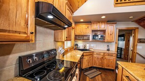 A kitchen with wooden cabinets, a black stove, and a granite countertop. - Hot Tub! Close to Fishing, ATV, Hiking, Rafting, Rivers! (Pagosa Springs)
