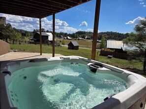 A hot tub with a clear view of a rural landscape, including houses and a forest in the background.