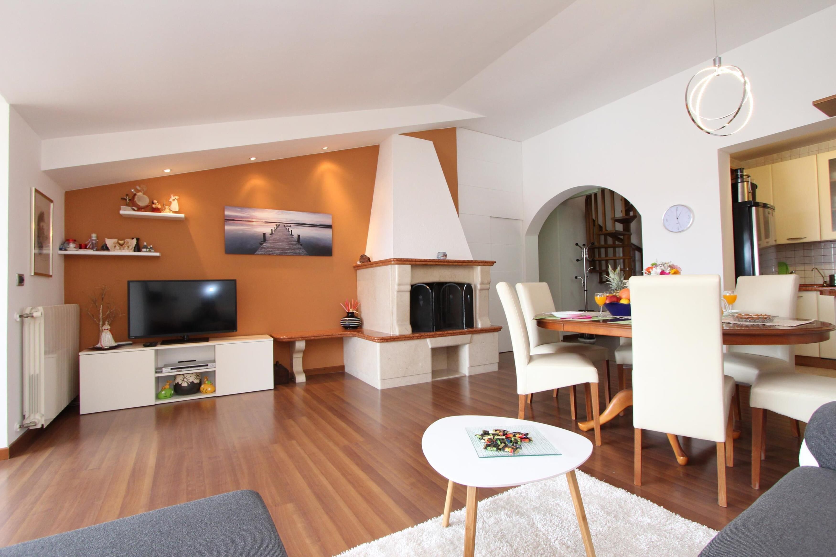 A modern living room with a fireplace, television, and dining area.