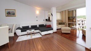 Een moderne woonkamer met een hoekbank, een klein rond tafeltje en een witte fauteuil.