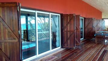 A wooden deck with sliding glass doors leading to a covered outdoor area.