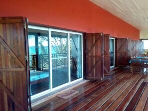 A wooden deck with sliding glass doors leading to a covered outdoor area. - Zara Village (Nosy Be)