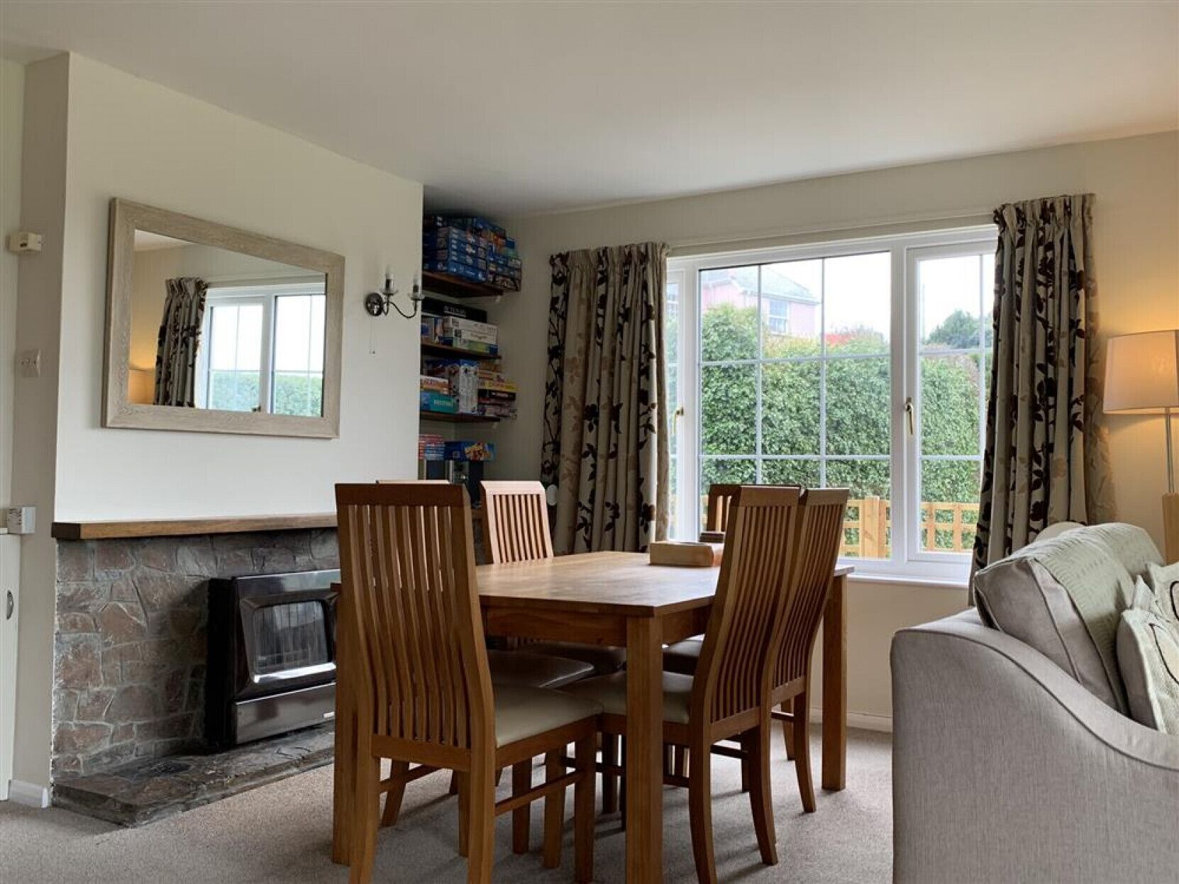 A dining area with a stone fireplace, wooden dining table, and chairs.