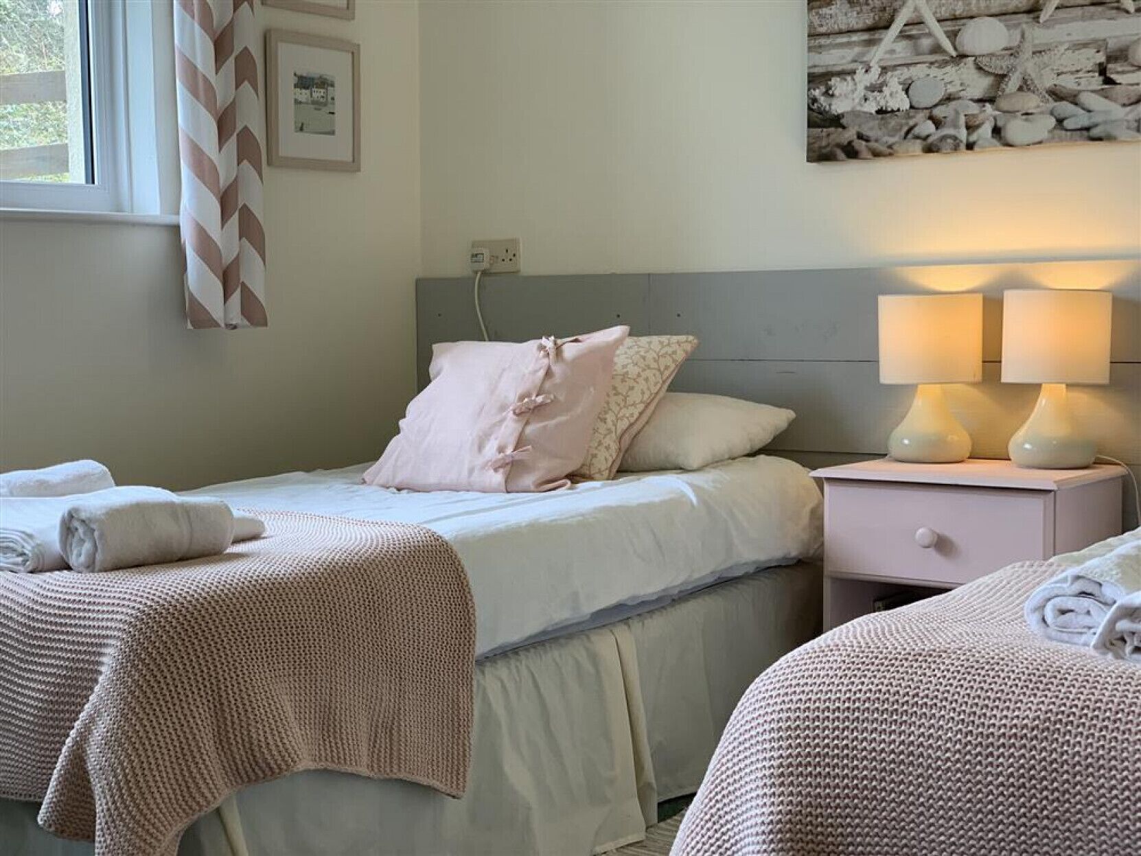 A bedroom with a bed, two bedside tables, a nightstand, and a wall-mounted lamp.