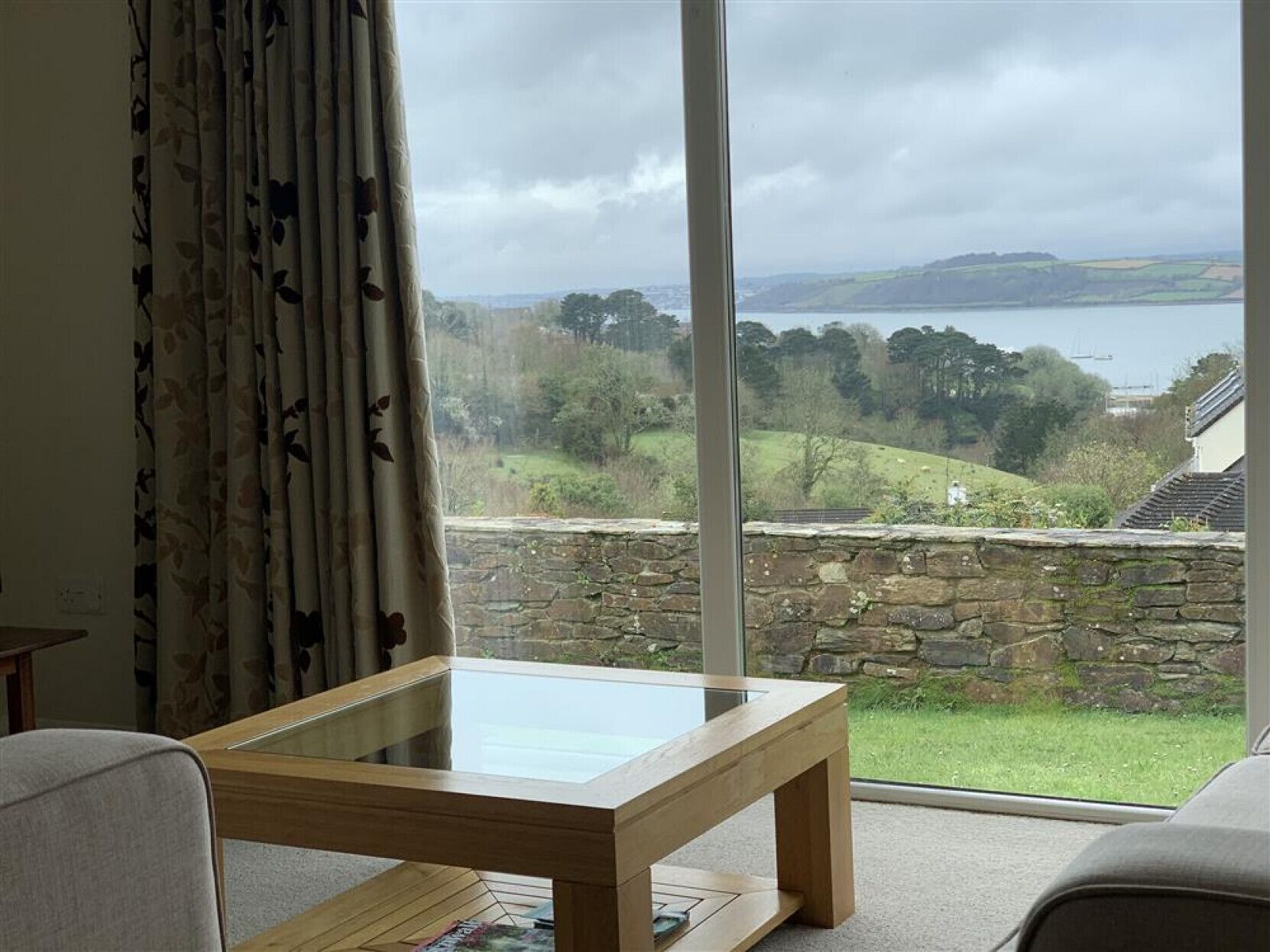 A room with a large window offering a view of a lake and surrounding landscape.