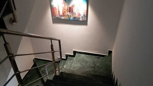 A staircase with a handrail and a painting on the wall. - LAZY BEAR VILLA  IN  LAP OF NATURE (GREATOR NOIDA)