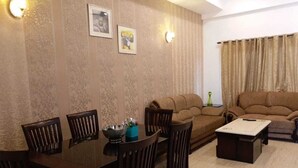 A living room with a sofa, a coffee table, and a dining table with chairs. - LAZY BEAR VILLA  IN  LAP OF NATURE (GREATOR NOIDA)