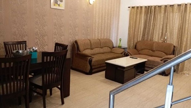 A living room with a sofa, chairs, a coffee table, and a dining table. - LAZY BEAR VILLA  IN  LAP OF NATURE (GREATOR NOIDA)