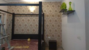 A room with a bunk bed, patterned wallpaper, a ceiling fan, and a shelf with decorative items. - LAZY BEAR VILLA  IN  LAP OF NATURE (GREATOR NOIDA)
