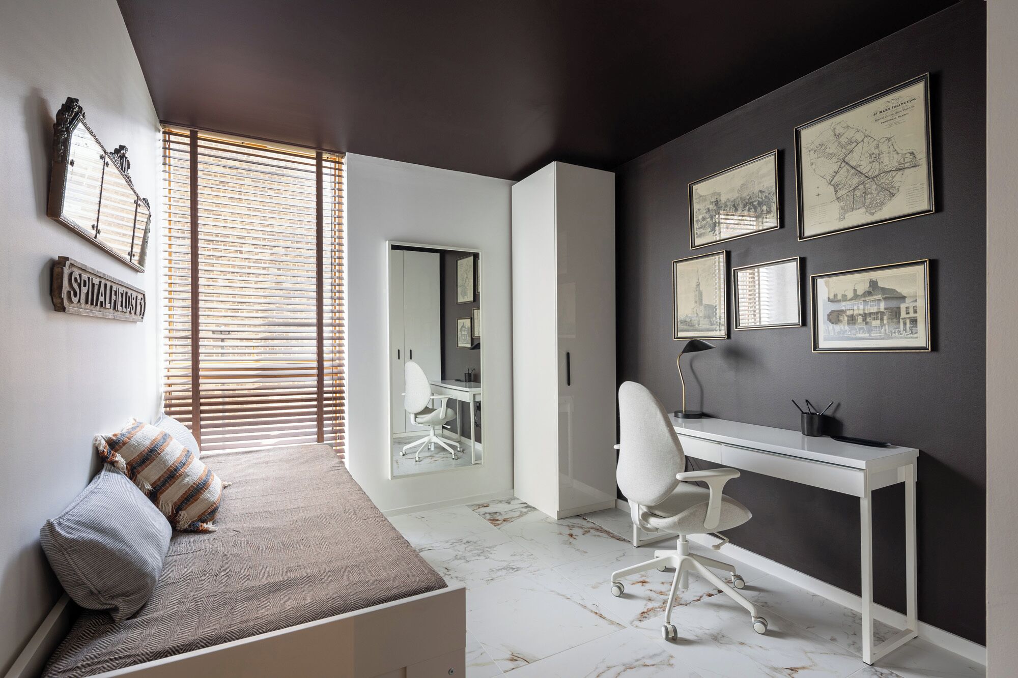 A modern office space with a desk, chair, and a seating area with a bench and pillows.