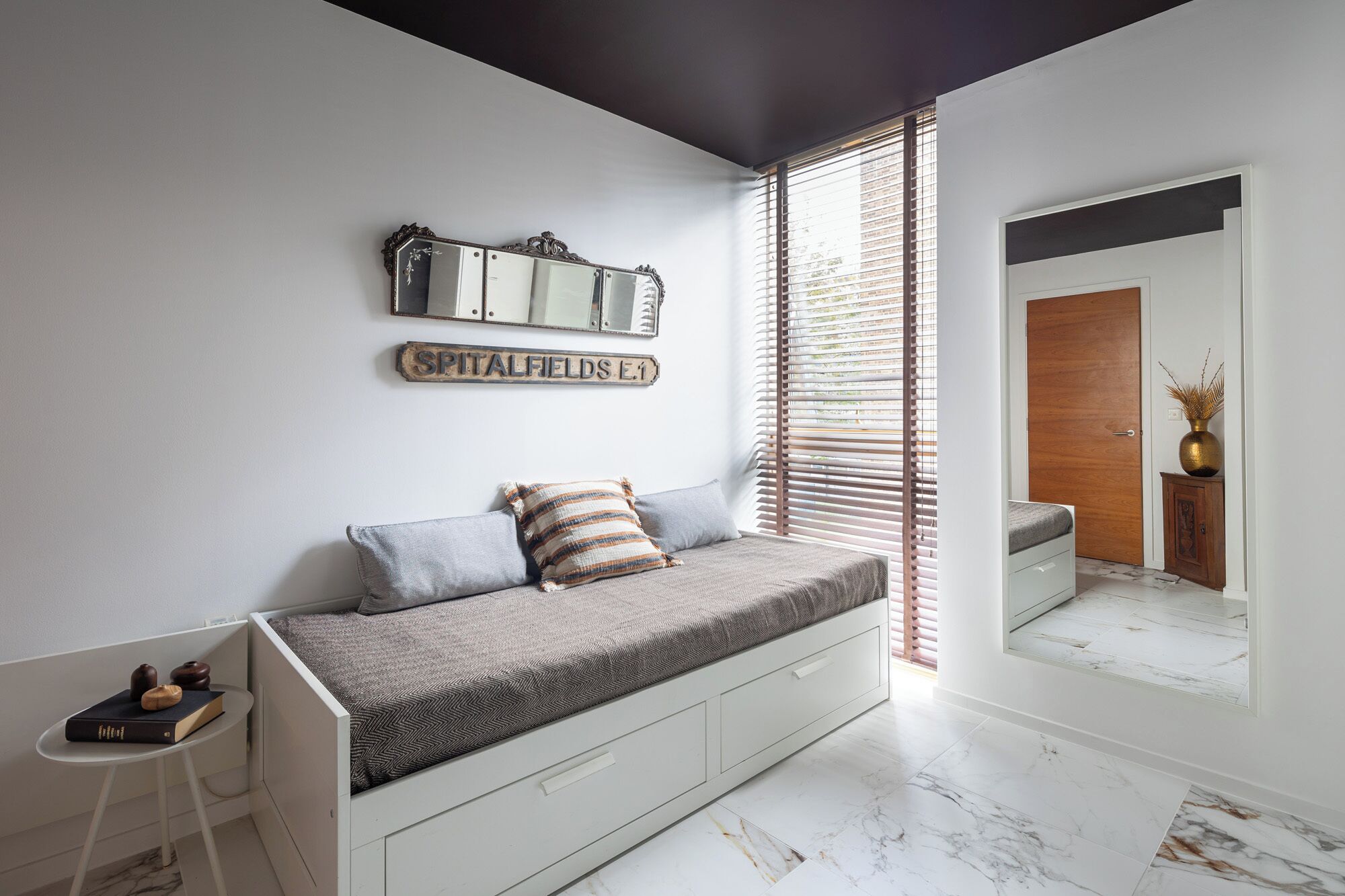 A modern living room with a built-in bench, a decorative mirror, and a sign on the wall.