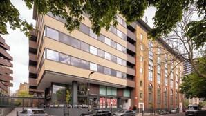 Un edificio moderno con fachada de ladrillo, ventanas grandes y escaparate con letrero de una cafetería.