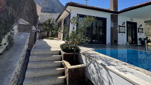 A modern house with a swimming pool, stone steps, and a mountain view. - Esiyok Villa in Antalya with heated pool (Hisarcandir Mahallesi Konyaalti)