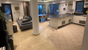 A spacious living area with a large sofa, a dining table, and a kitchen area with a modern design. - Esiyok Villa in Antalya with heated pool (Hisarcandir Mahallesi Konyaalti)
