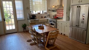 A kitchen with wooden flooring, a dining table with chairs, a refrigerator, and a stove. - 1940s Brooklyn Cottage Townhouse (Brooklyn)