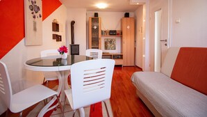 Ein modernes Wohnzimmer mit einer Couch, einem Esstisch mit Stühlen und einer Küchenzeile mit Schränken und einem Kühlschrank.