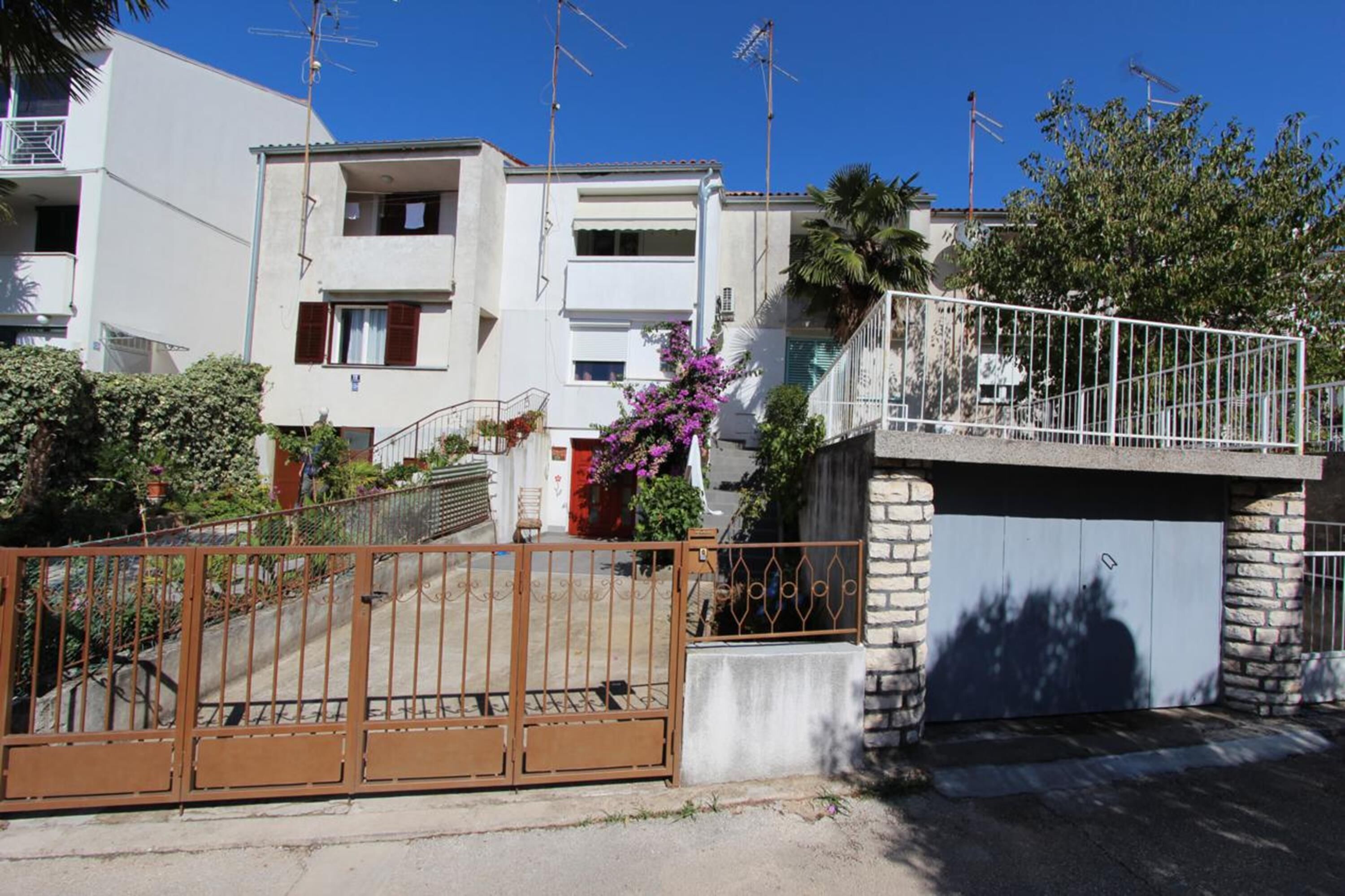 Ein Wohngebäude mit geschlossenem Eingangsbereich, einem Balkon und einer Garage.