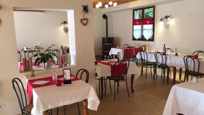 A dining area with tables set for two, featuring white tablecloths and red napkins. - Le Grand Joly (Sainte-Agnès)